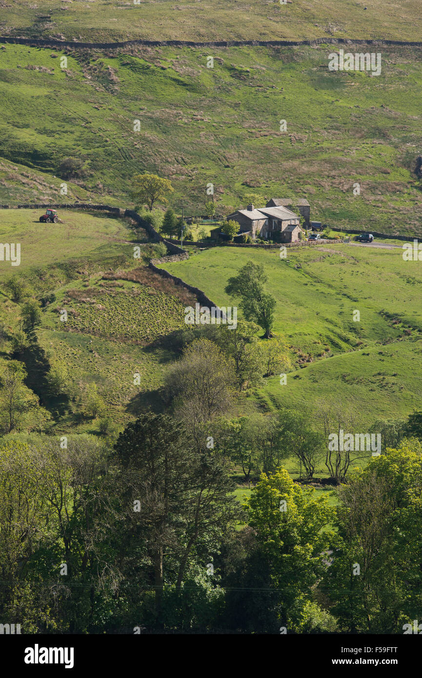 Sunny, high view over the fells in the valley of Dentdale, Cumbria, England, UK - isolated farm & tractor working in a field on steep-sided hillside. Stock Photo