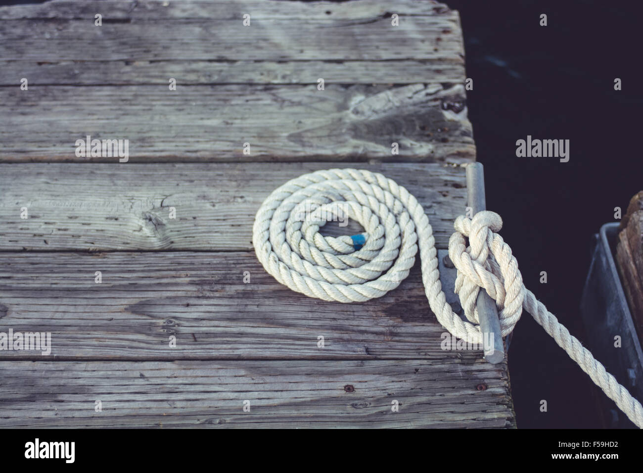 Nautical rope perfectly wound and coiled on an old weathered dock. Stock Photo