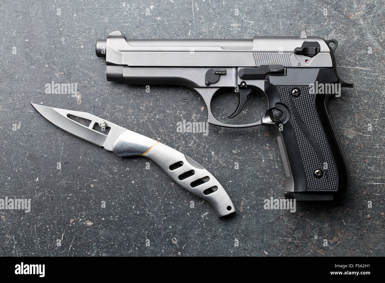 handgun and knife on old background Stock Photo