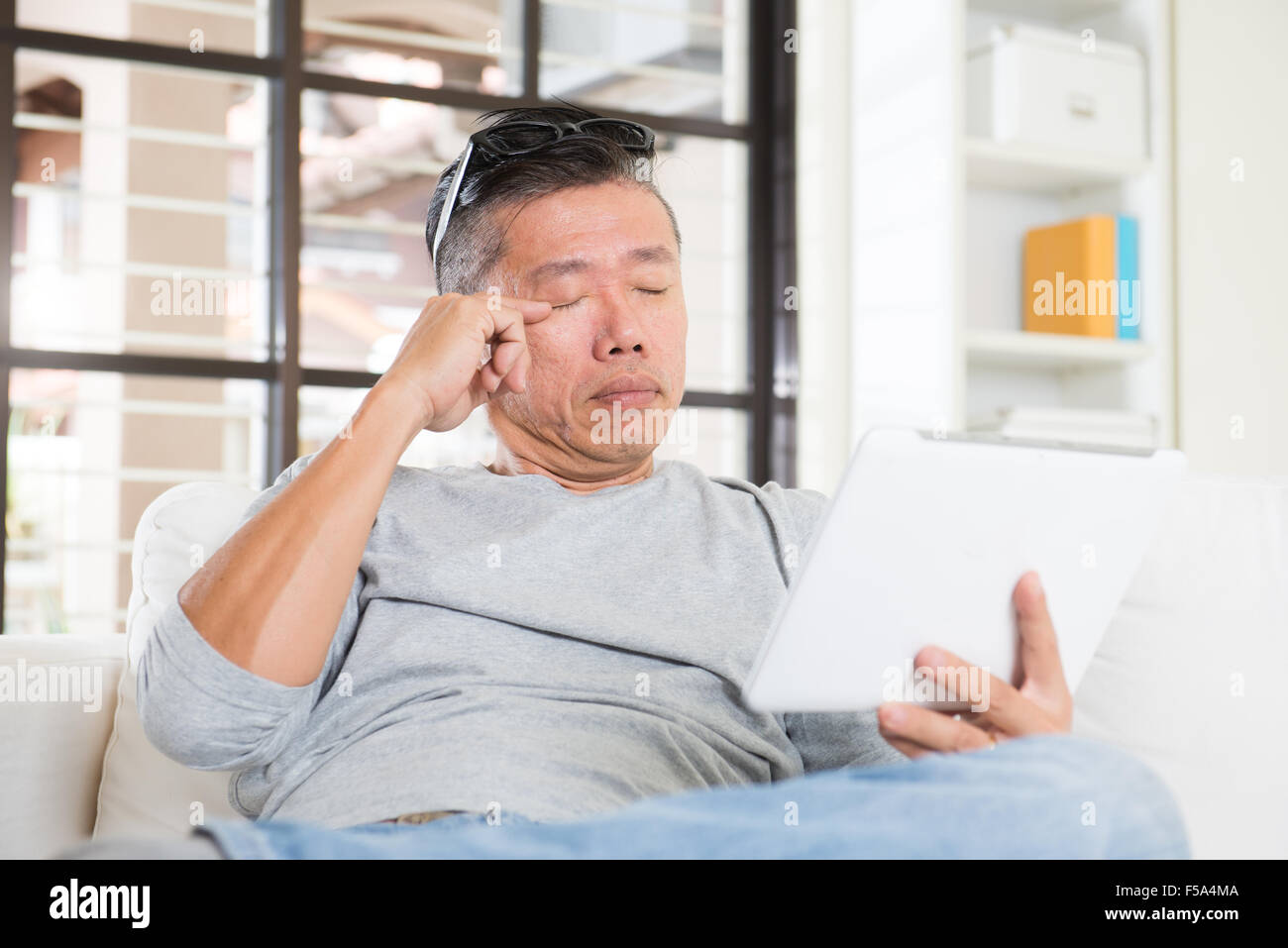 asian man with eyes problem after long hours of using computer tablet ...