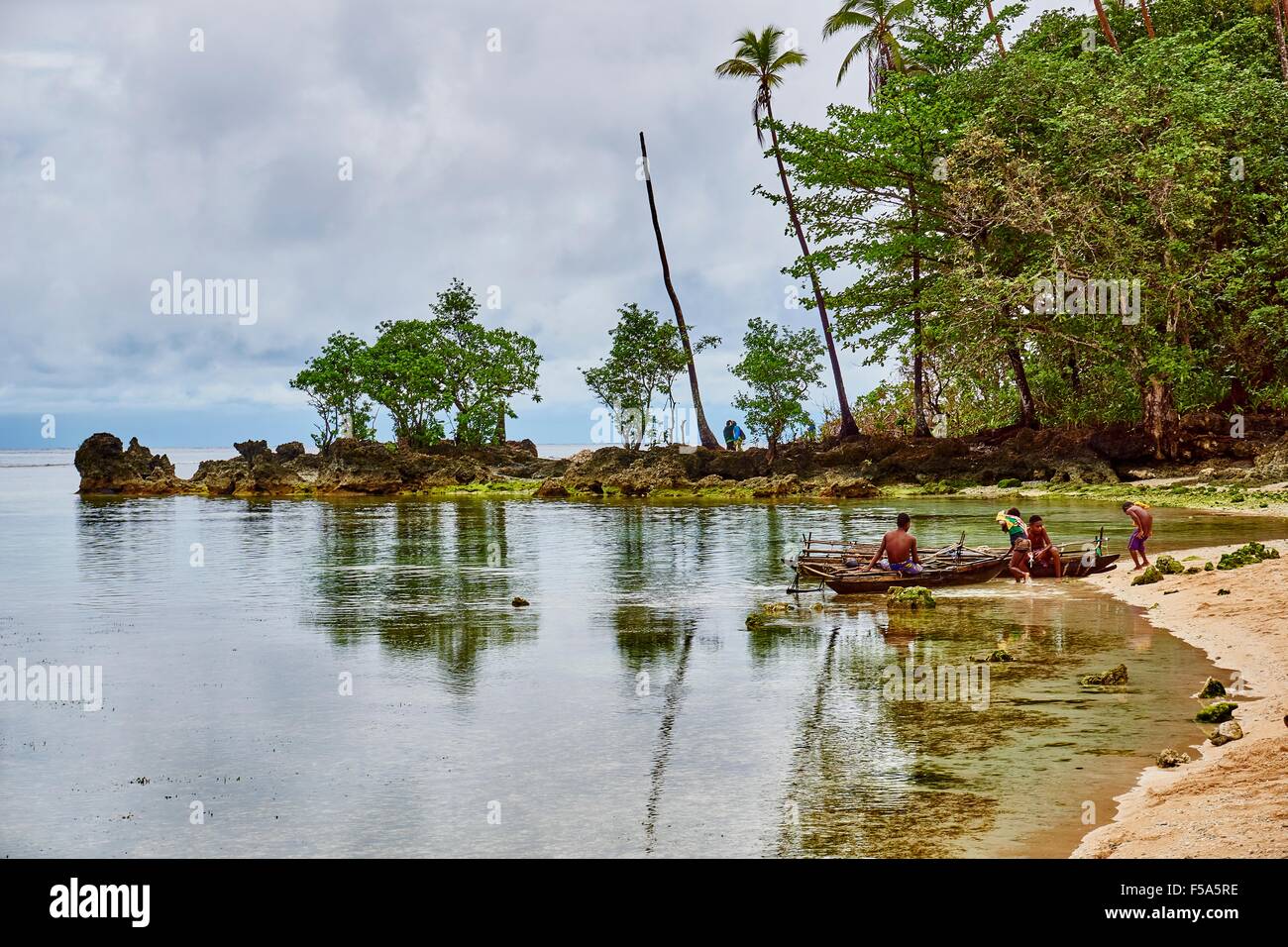 Islanders with canoes on beach at Kiriwina Island PNG Stock Photo