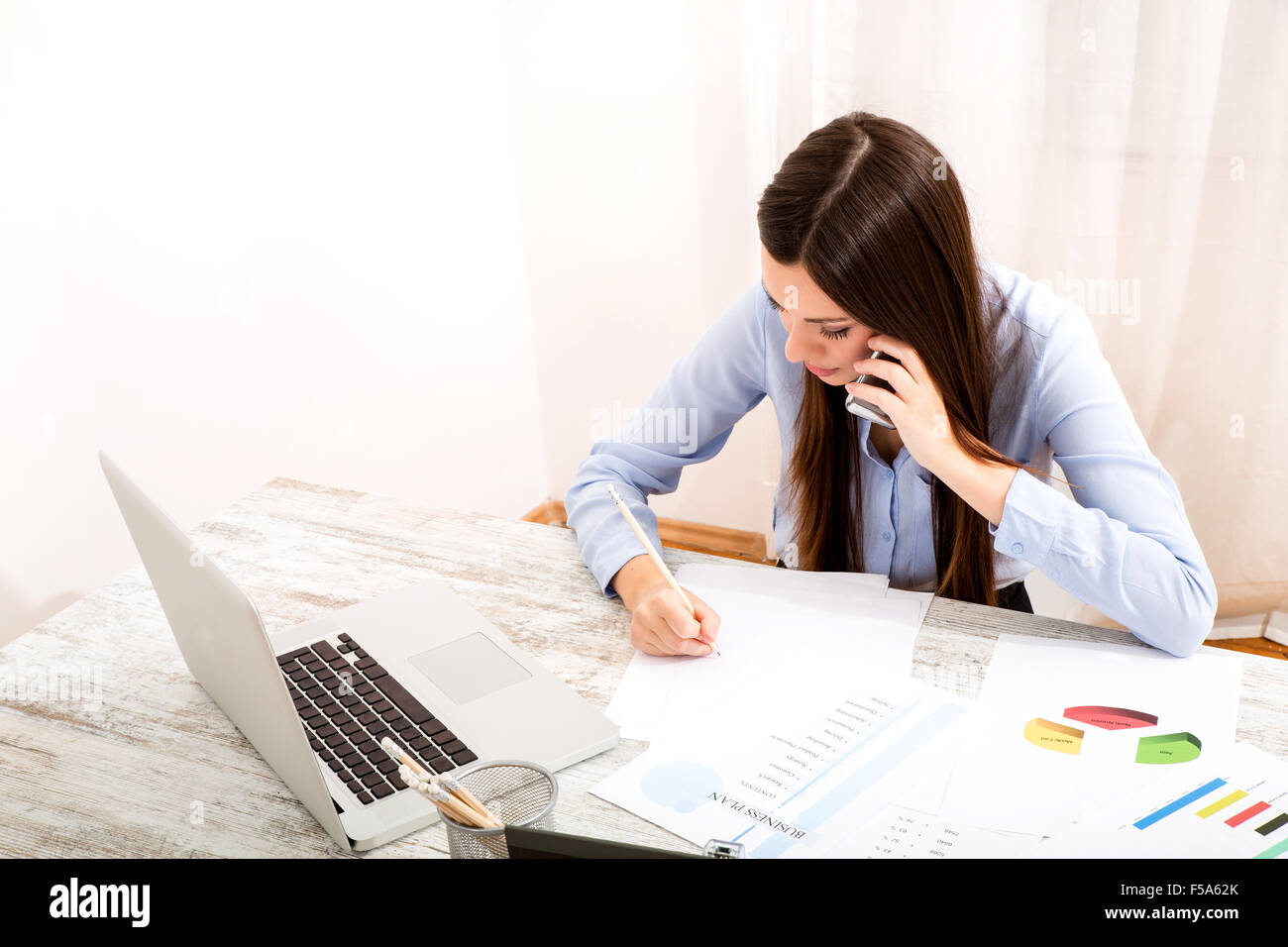 Businesswoman working at the office with the laptop and talking by phone Stock Photo