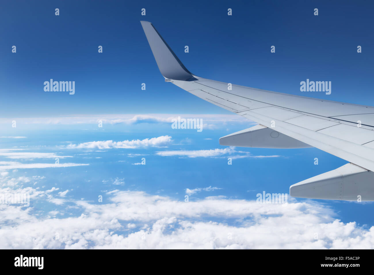 Airplane wing in the sky flying above clouds. Stock Photo