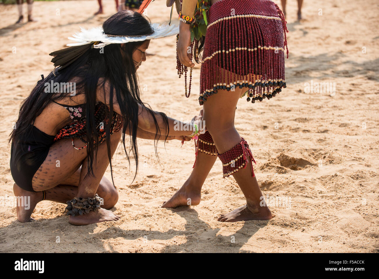 Palmas, Tocantins State, Brazil. 29th October, 2015. An indigenous Brazilan girl ties a beaded anklet round the leg of a fellow competitor at the International Indigenous Games, in the city of Palmas, Tocantins State, Brazil. Credit:  Sue Cunningham Photographic/Alamy Live News Stock Photo
