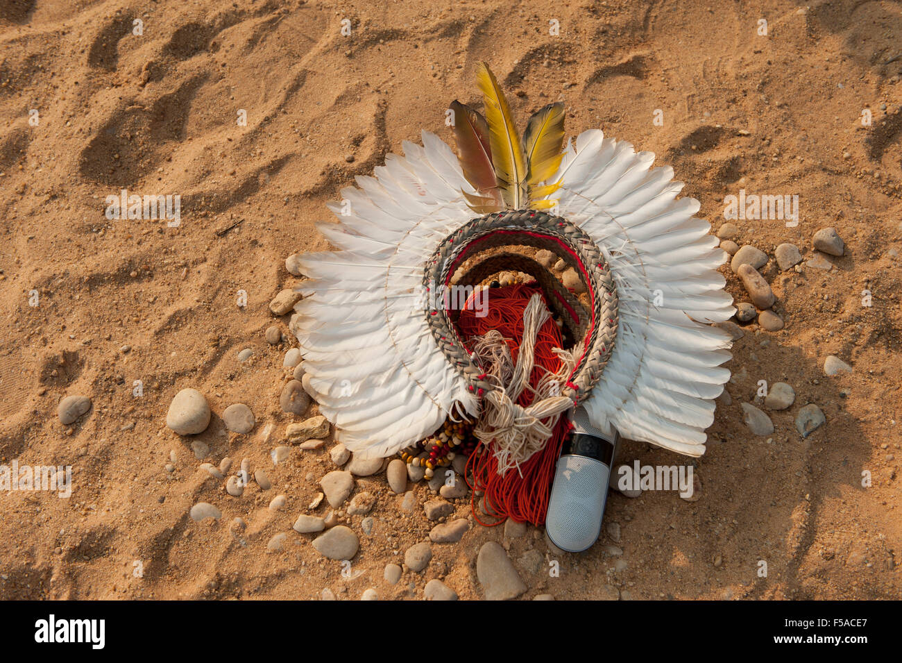 A white feather cokaa headdress lies on the ground with the owner's iPhone speaker at the International Indigenous Game, in Brazil. 30th October 2015 Stock Photo
