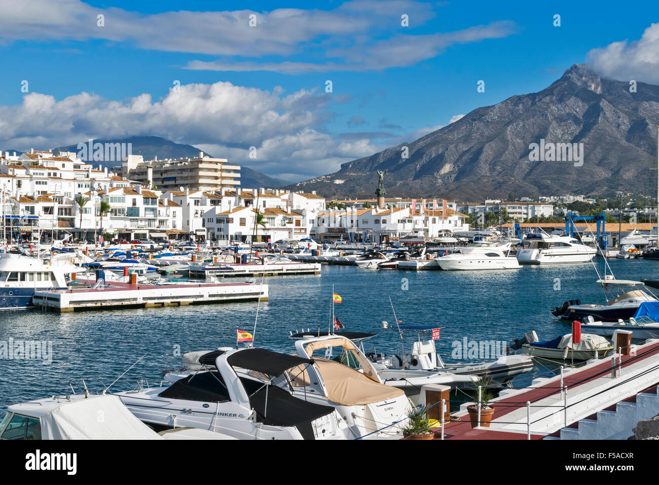 PUERTO BANUS ANDALUCIA SPAIN HARBOUR AND BOATS WITH MOUNTAINS AND CLOUDS Stock Photo