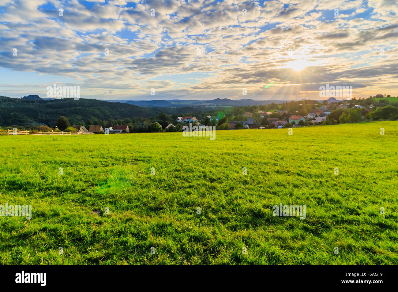 Beautiful sunset over countryside landscape of rolling hills with sun beams piercing sky and lighting hillside Stock Photo