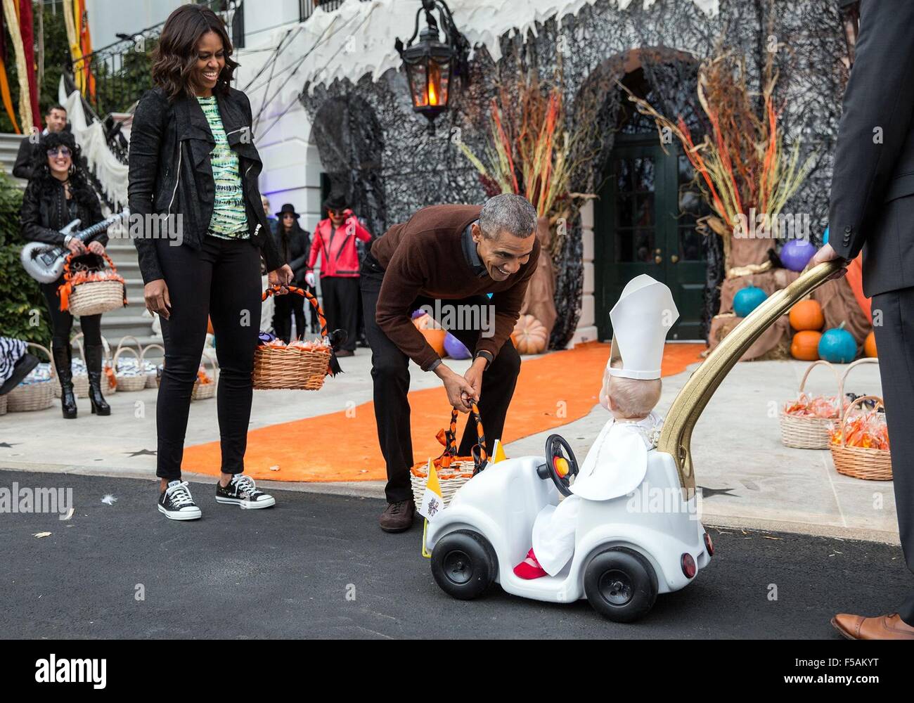 Washington, DC, USA. 31st Oct, 2015. US President Barack Obama and First  Lady Michelle Obama react to a young child dressed in a pope costume while  handing out Halloween treats to local