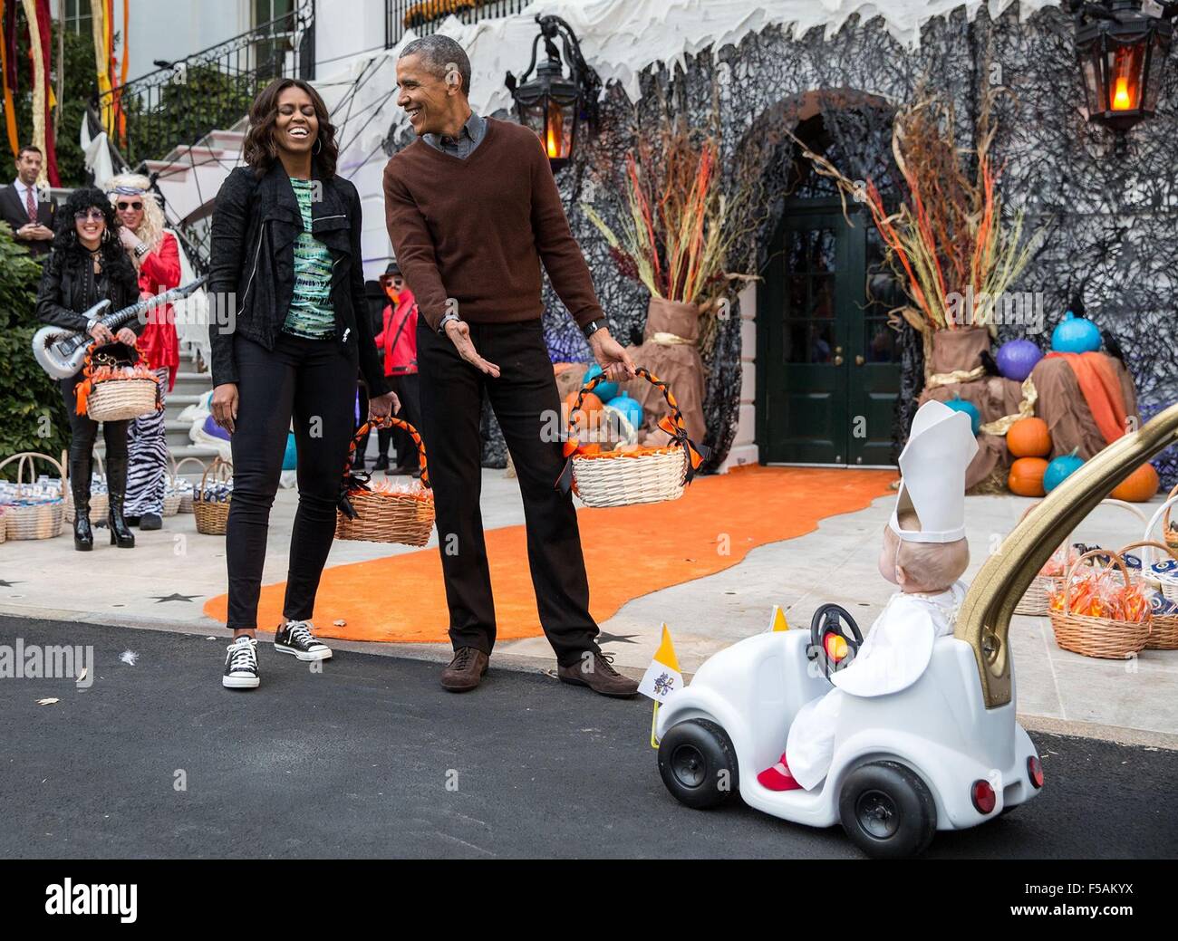 Washington, DC, USA. 31st Oct, 2015. US President Barack Obama and First Lady Michelle Obama react to a young child dressed in a pope costume while handing out Halloween treats to local children and children of military families on the South Lawn of the White House October 31, 2015 in Washington, DC. Stock Photo