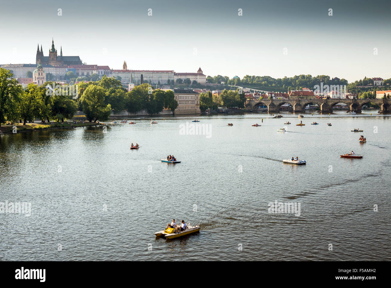 People in paddle boats in Vltava River, Prague castle and Charles