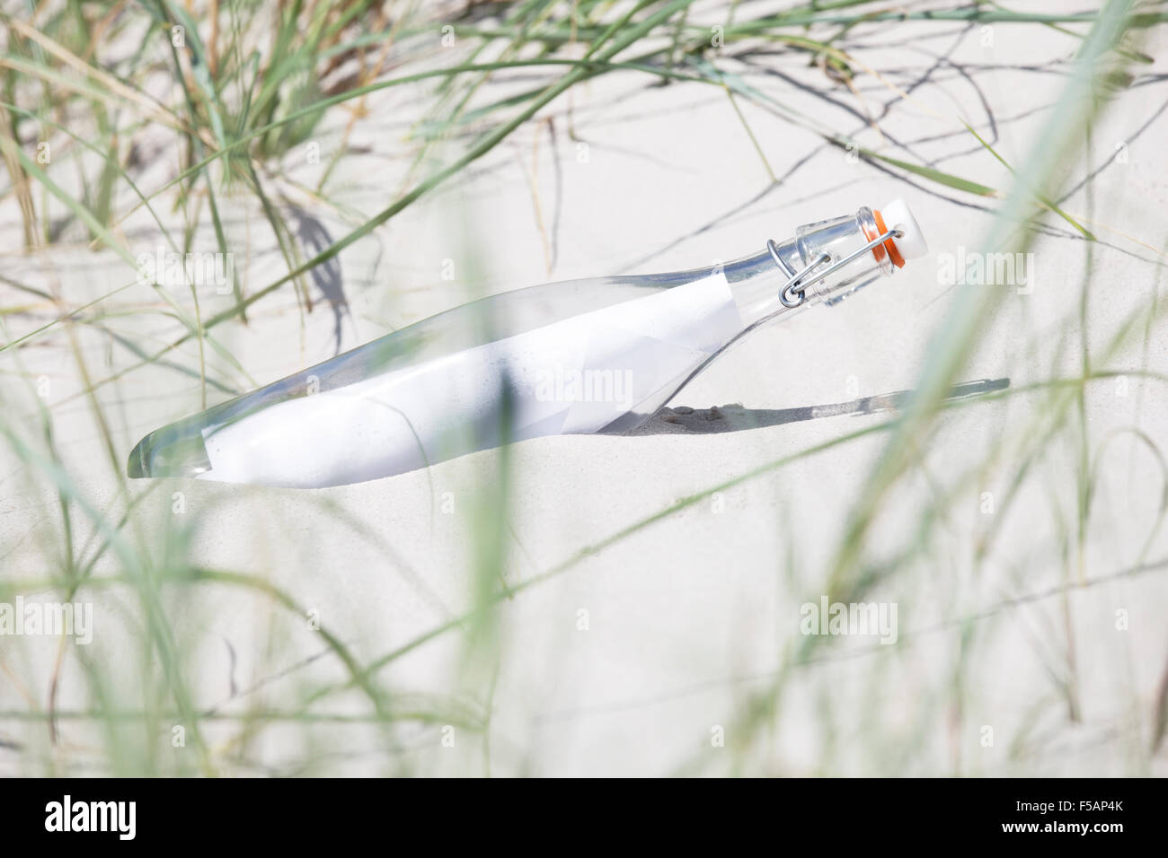 a bottle with a paper lying in the sand on a beach Stock Photo