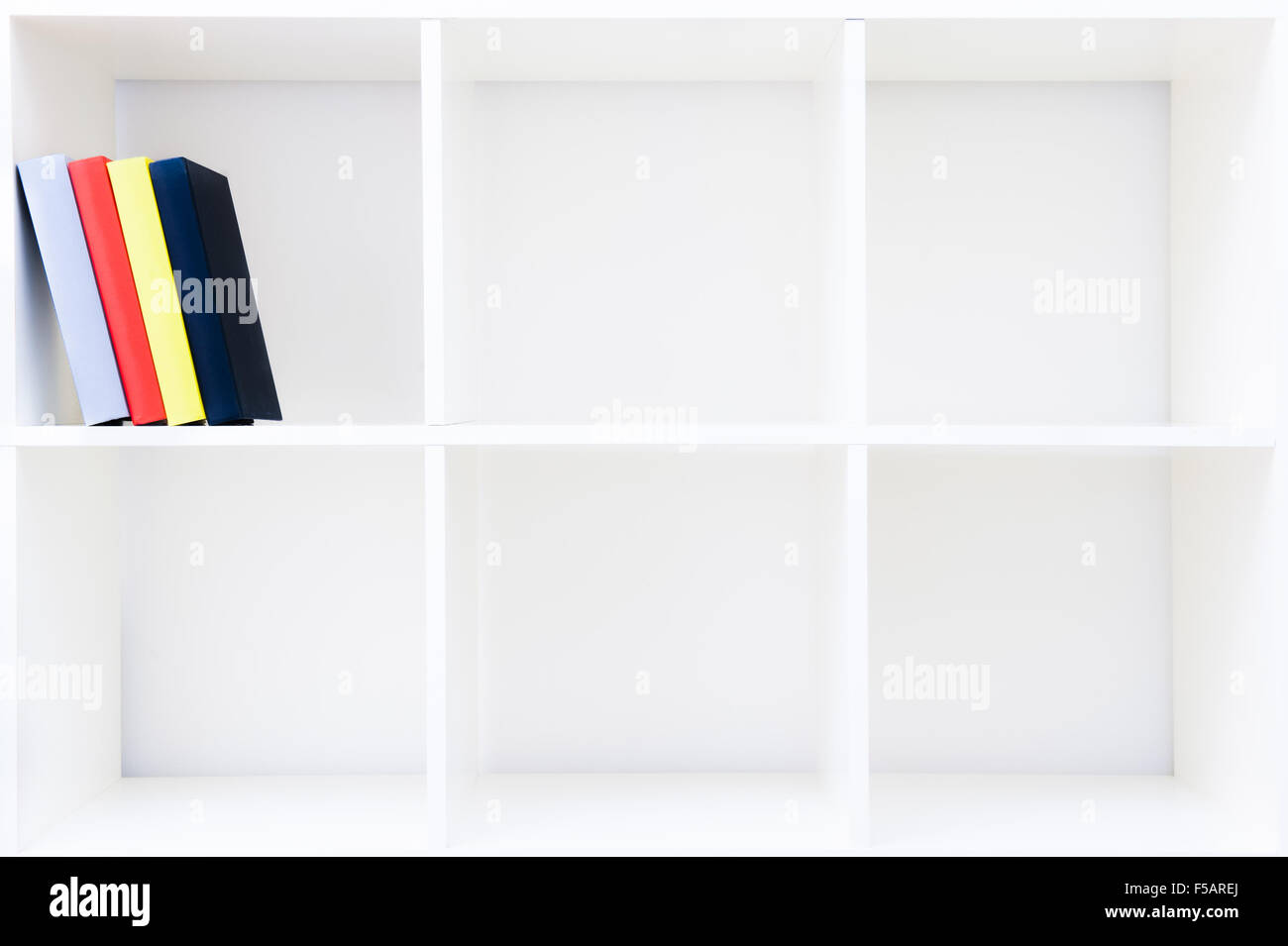 Colored books red yellow and blue on cubical white bookshelf with empty copy space Stock Photo