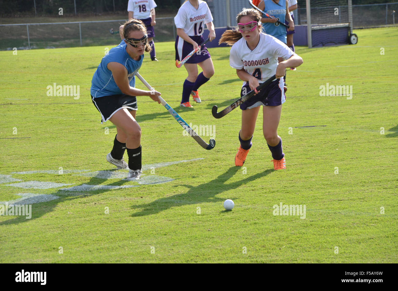 Girls playing field hockey in a high school game Stock Photo