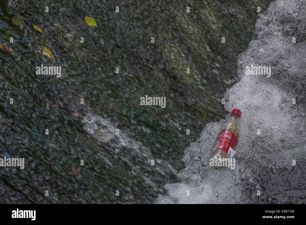 Empty soft drinks bottle caught in cascading weir flow. Plastic waste, war on plastic concept. For environmental river pollution, plastic rubbish. Stock Photo