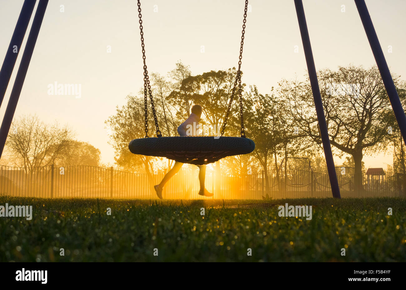 Mature Man Jogging Past Swing In Public Park On A Mist