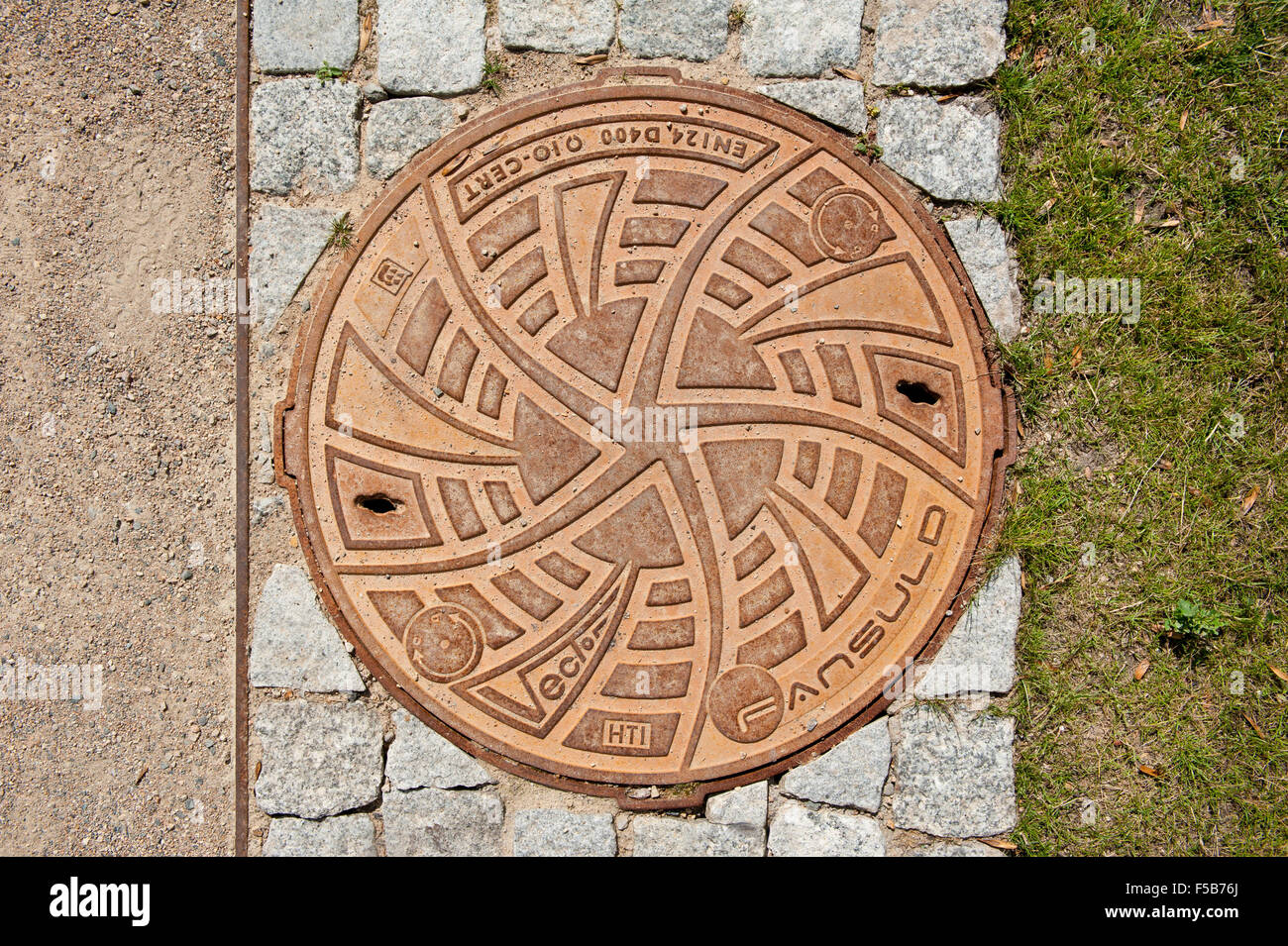 Ornamental brown manhole cover of sewage well by Fansuld in park Lazienki Krolewskie w Warszawie, Royal Baths Park, Warsaw... Stock Photo