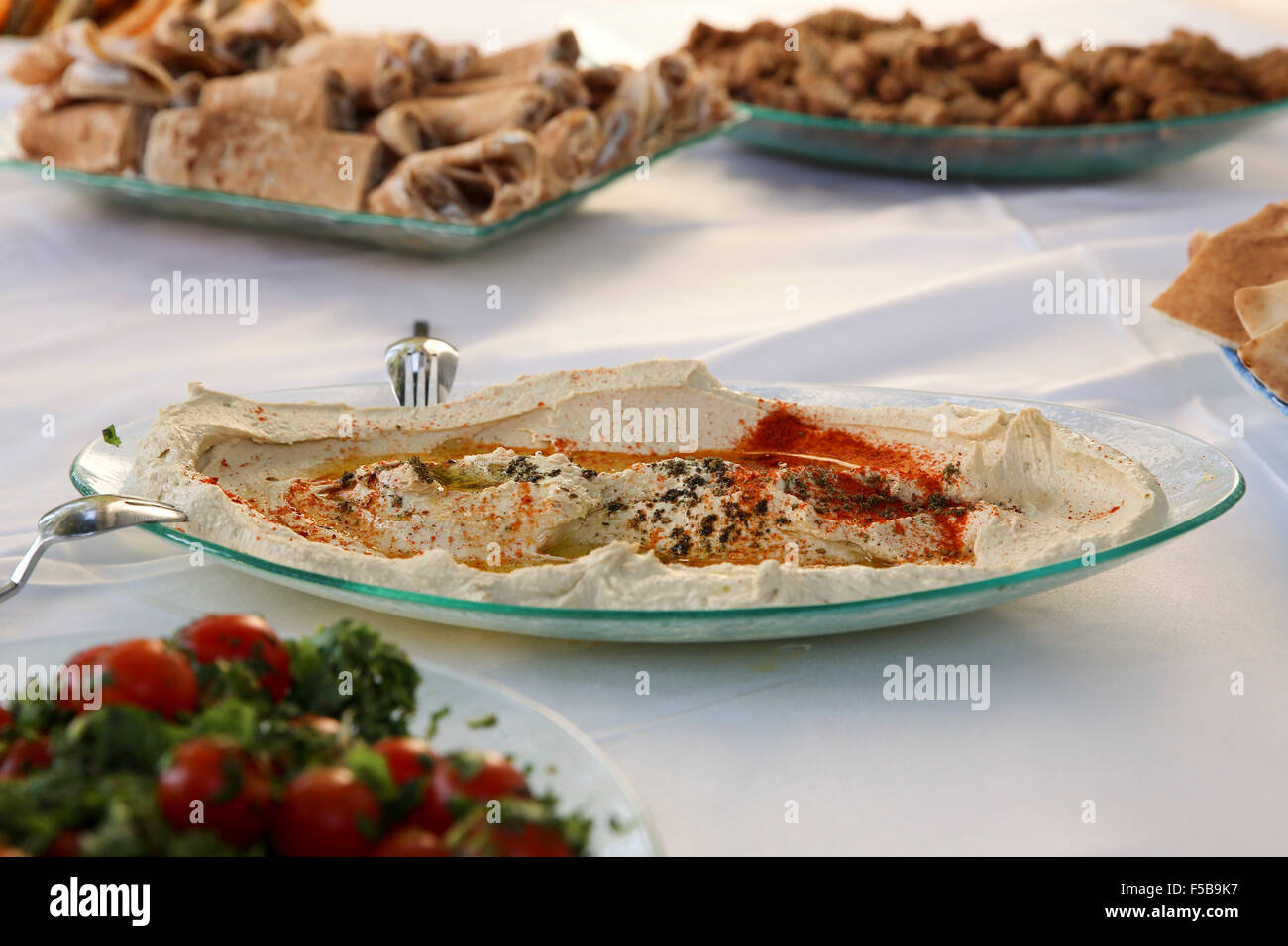 A buffet table set with salads and appetizers - main focus on a dish of hummus Stock Photo