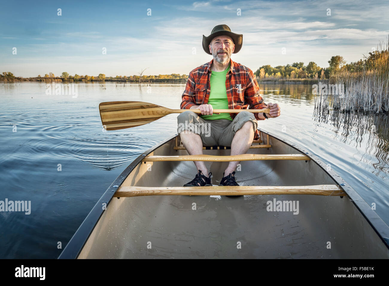 senior paddler enjoying paddling a canoe on a calm lake, Riverbend Ponds Natural Area, Fort Collins, Colorado Stock Photo