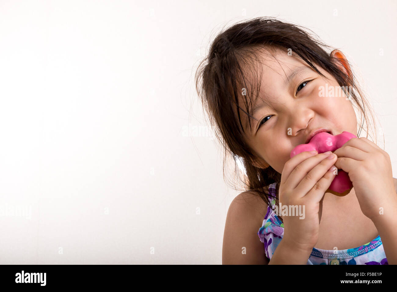 Little girl is eating her donut with happiness. Stock Photo