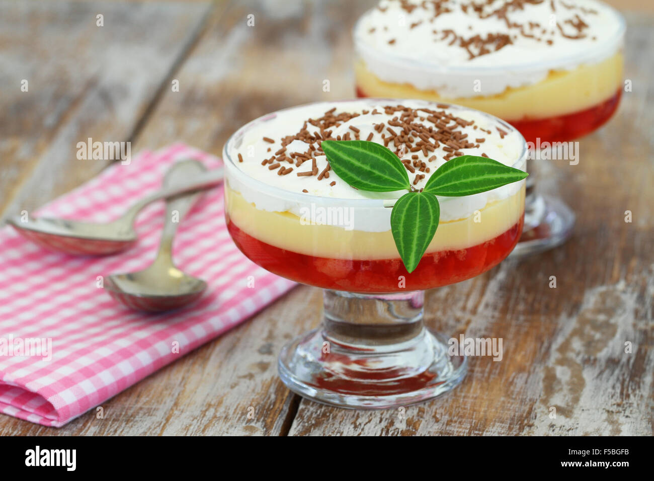 Traditional English strawberry trifle in transparent dessert glass on rustic wooden surface Stock Photo