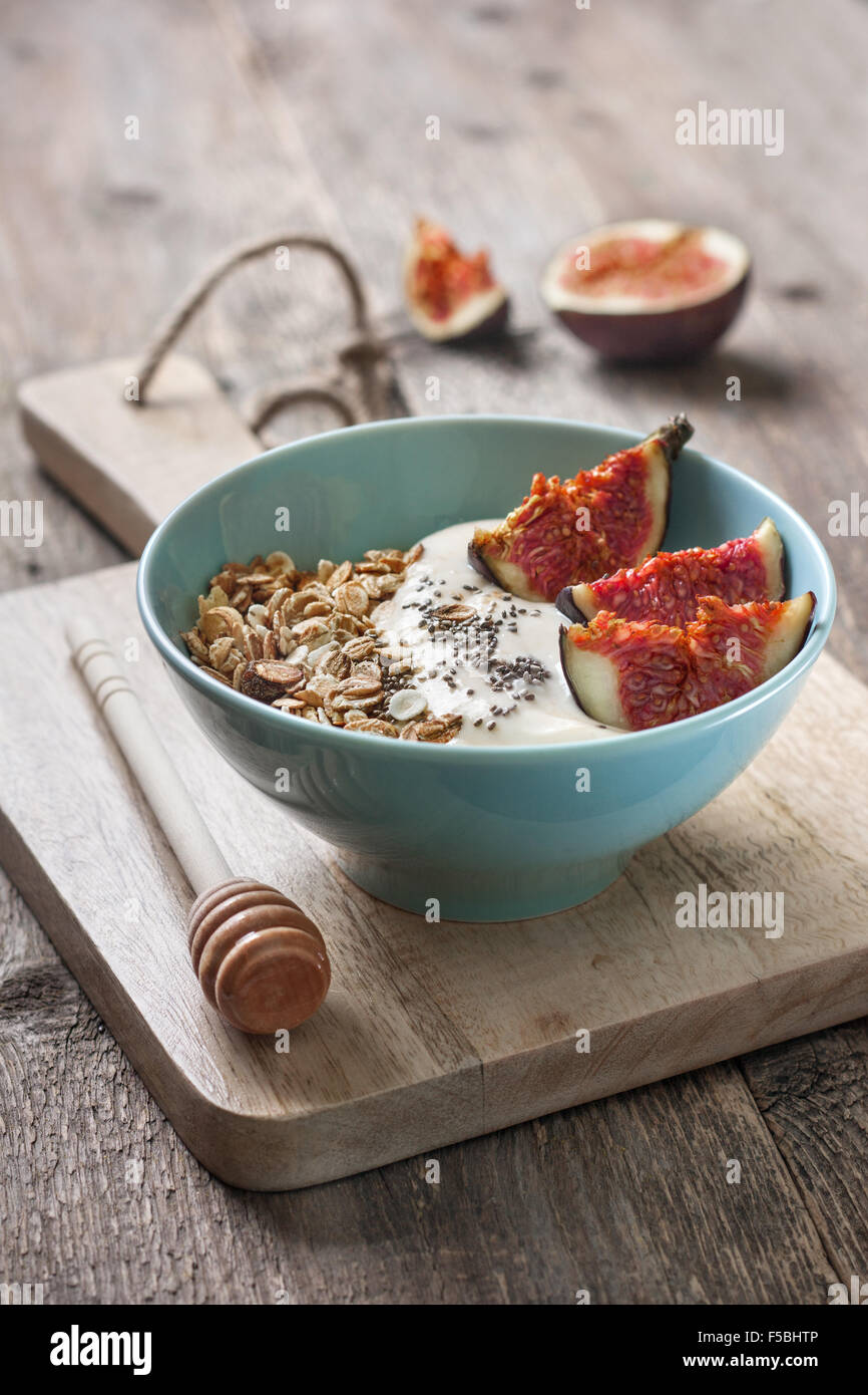 Breakfast with muesli, yogurt, figs and chia seeds in a blue bowl on a wooden background Stock Photo
