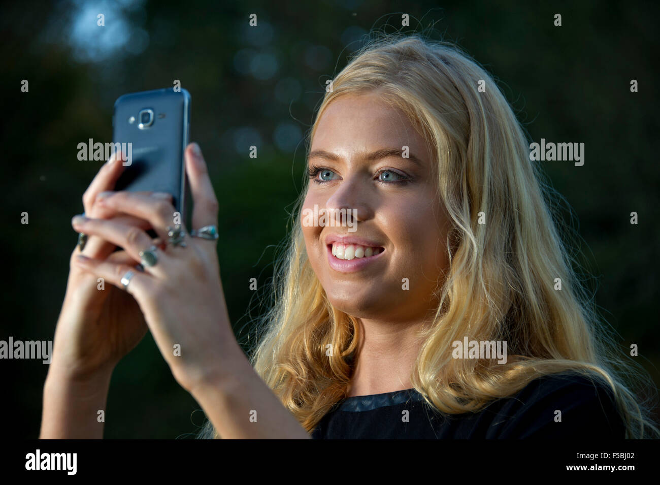 Young blonde woman using a mobile phone in the dark Stock Photo