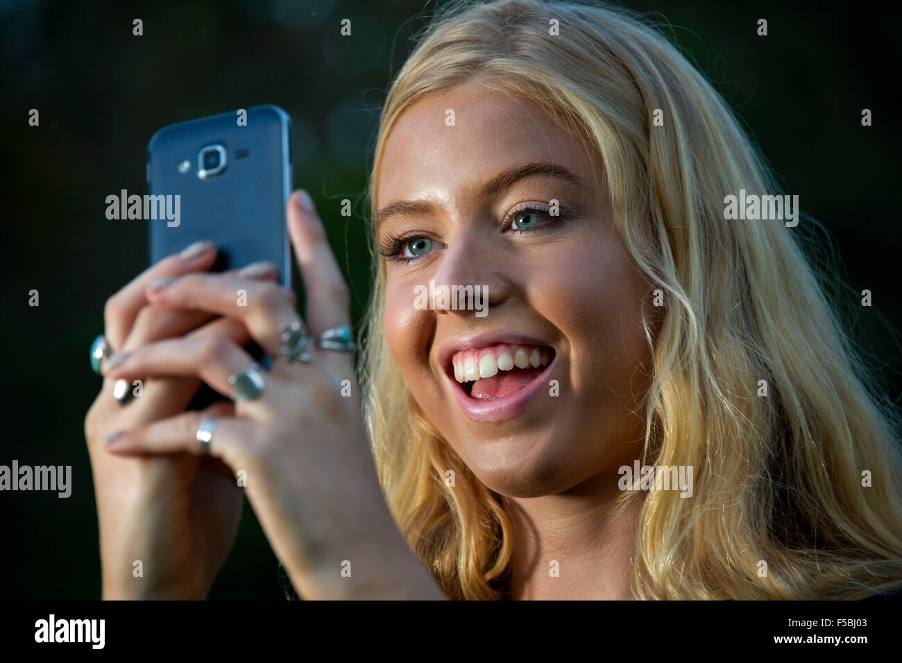 Young blonde woman using a mobile phone in the dark Stock Photo