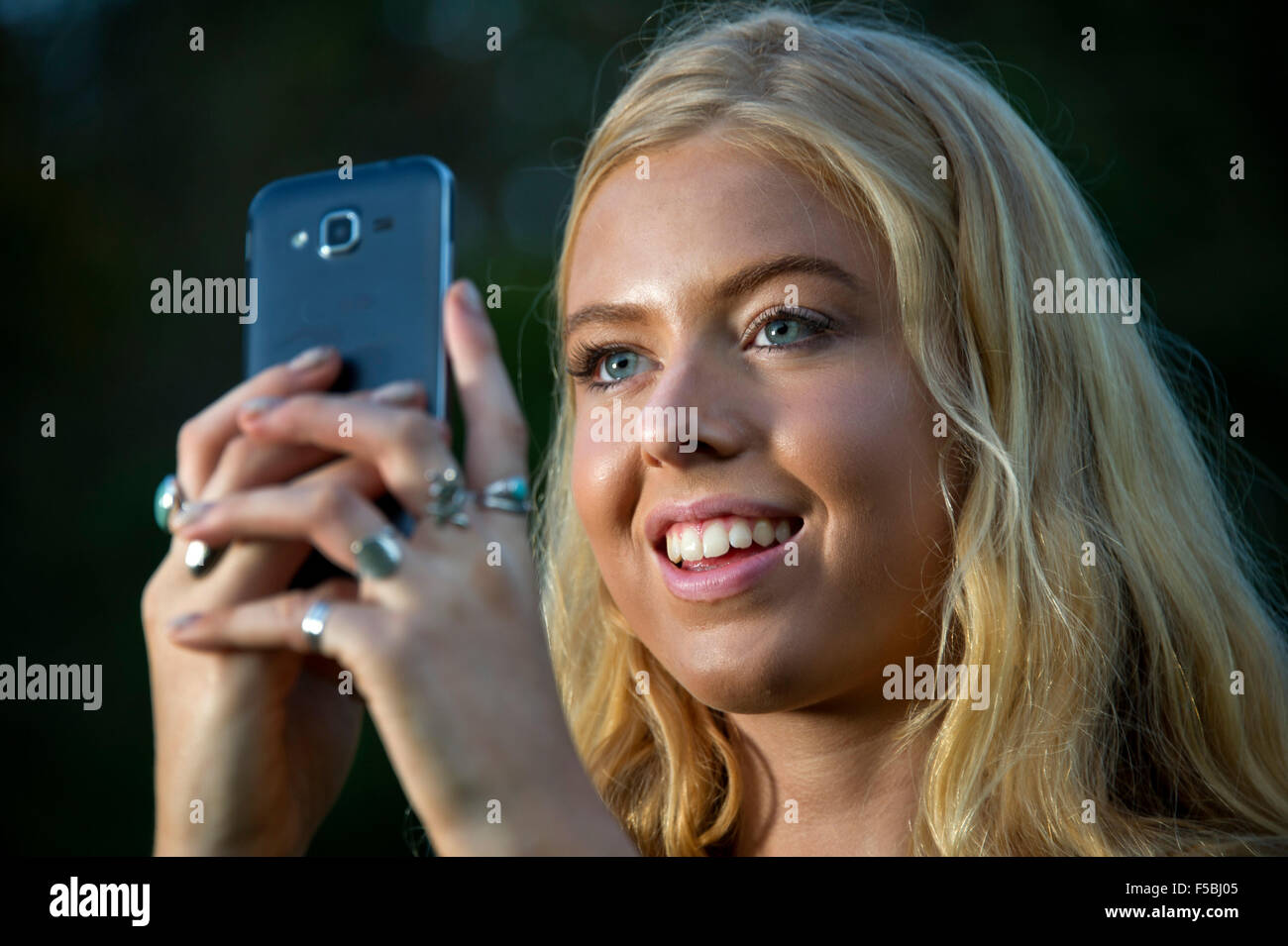 Young blonde woman using a mobile phone in the dark Stock Photo