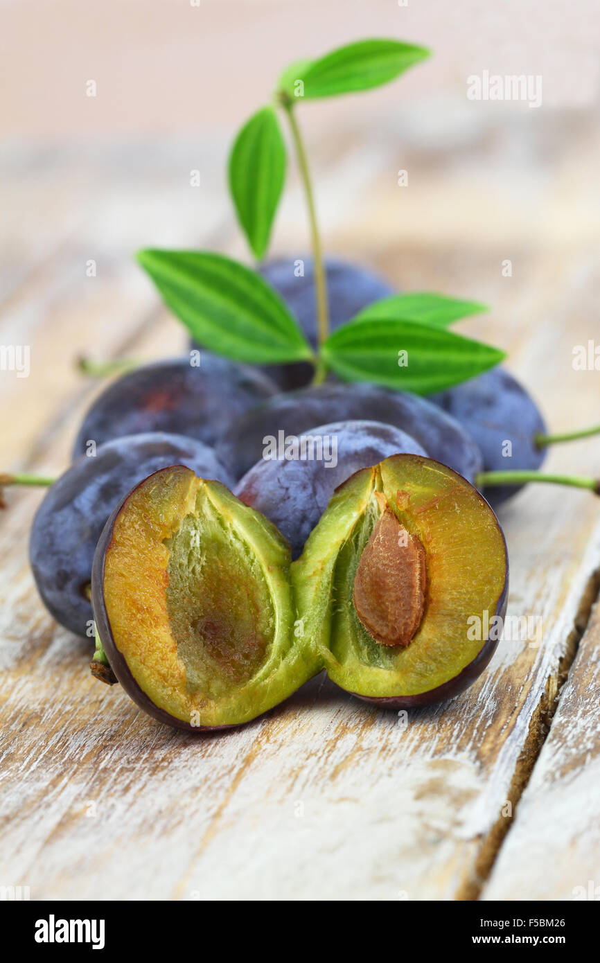 Juicy plums on rustic wooden surface, closeup Stock Photo