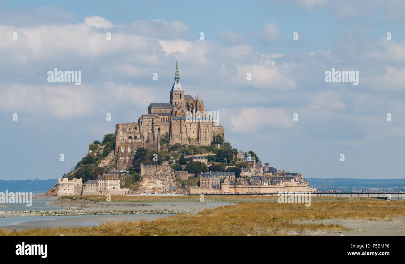 The island of Mont Saint-Michel in France with tourists walking across the new bridge to the abbey Stock Photo