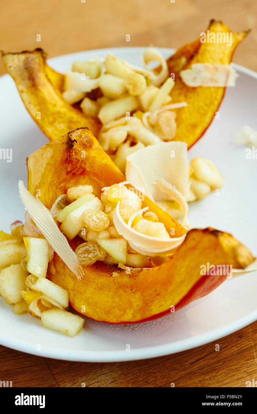 Roasted uchiki kuri squash on a plate with a pear salsa and soy cheese. Stock Photo