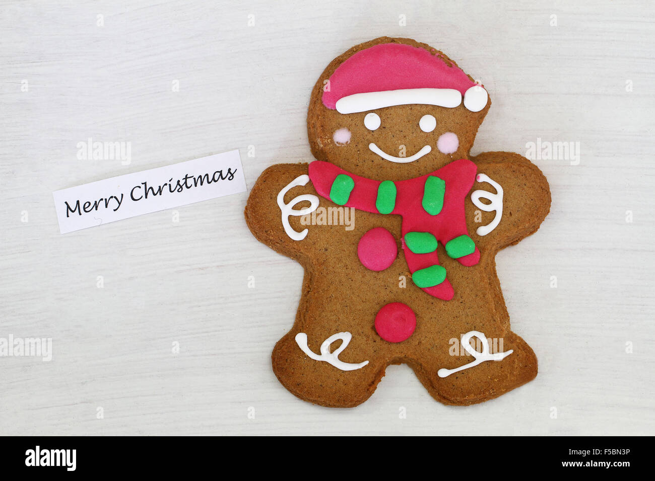 Merry Christmas card with gingerbread man on white wooden surface Stock Photo