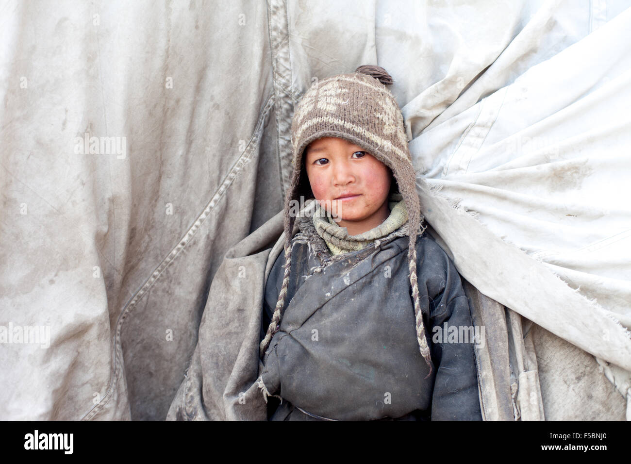 A cute little tibetan nomadic boy peering out from his tent at the winter pastures of Puga Stock Photo