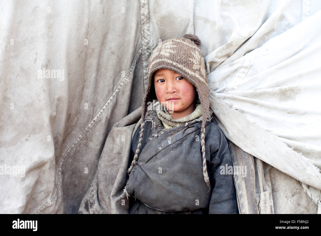 A cute little tibetan nomadic boy peering out from his tent at the winter pastures of Puga Stock Photo