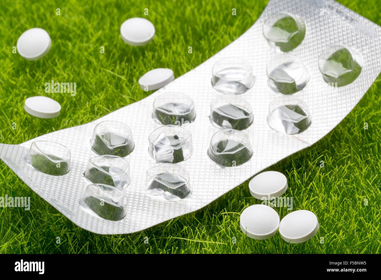 White pills and empty pill blister pack on the grass Stock Photo