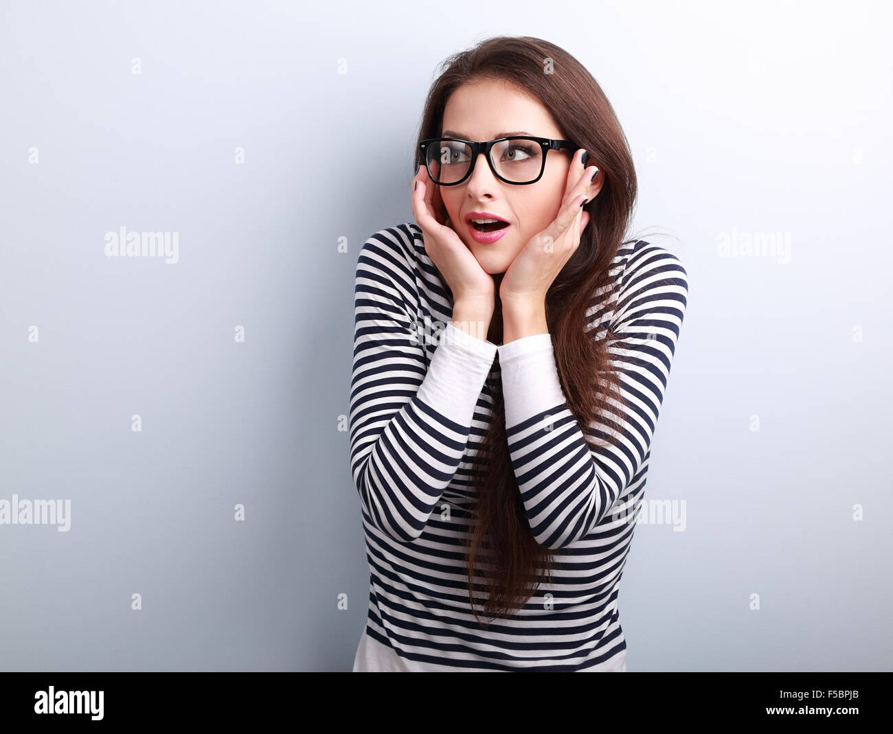 Fun surprising young woman in eyeglasses looking on empty copy space background Stock Photo