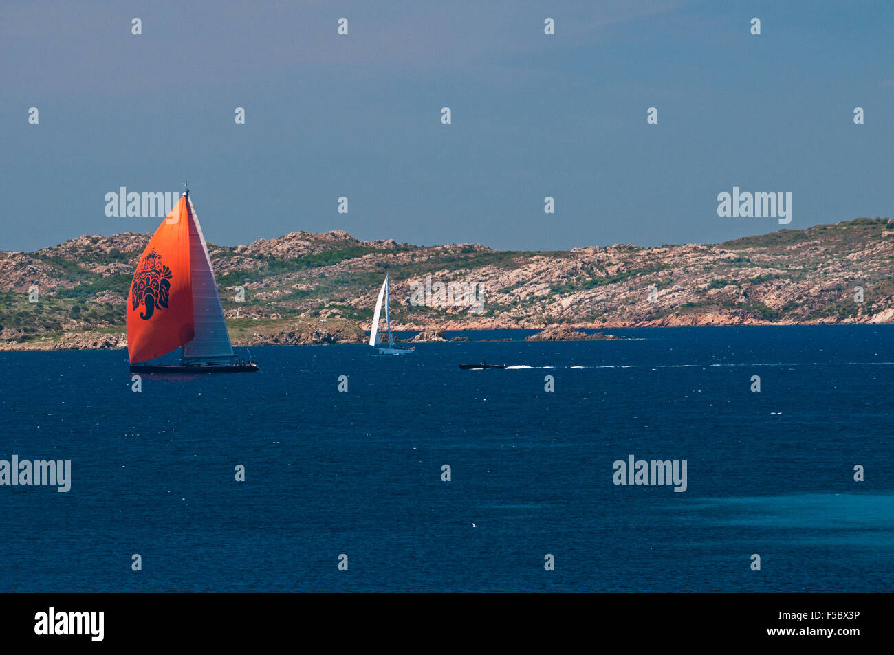 Caprera island,Sardinia, Italy, 5/2015.Red sail luxury yacht navigate along the coast of La Maddalena archipelago Stock Photo