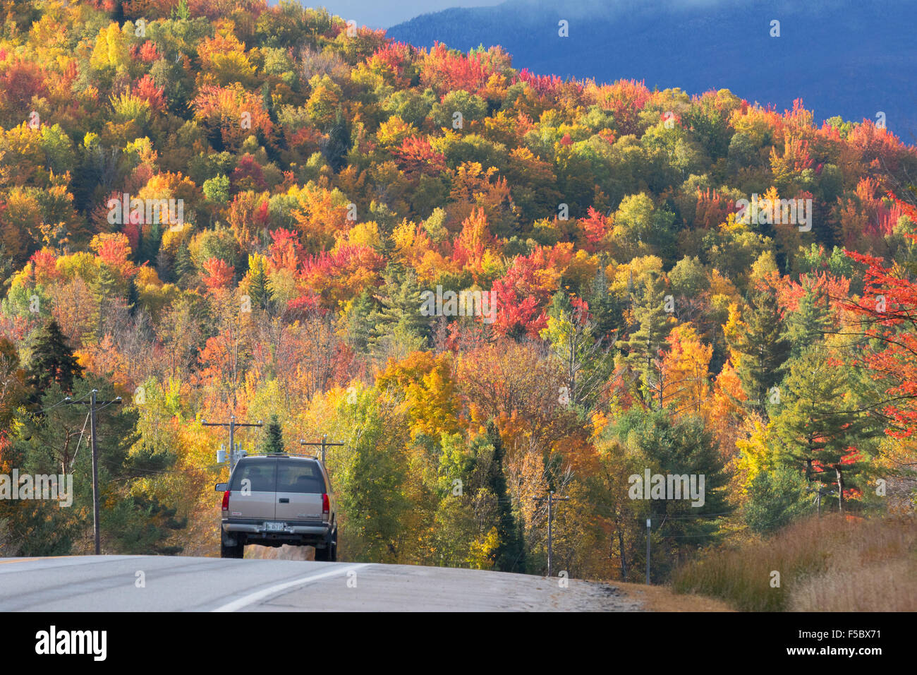 A car driving along the Kancamagus Highway, route 112, in New England in autumn, with colourful foliage, White Mountains New Hampshire USA Stock Photo