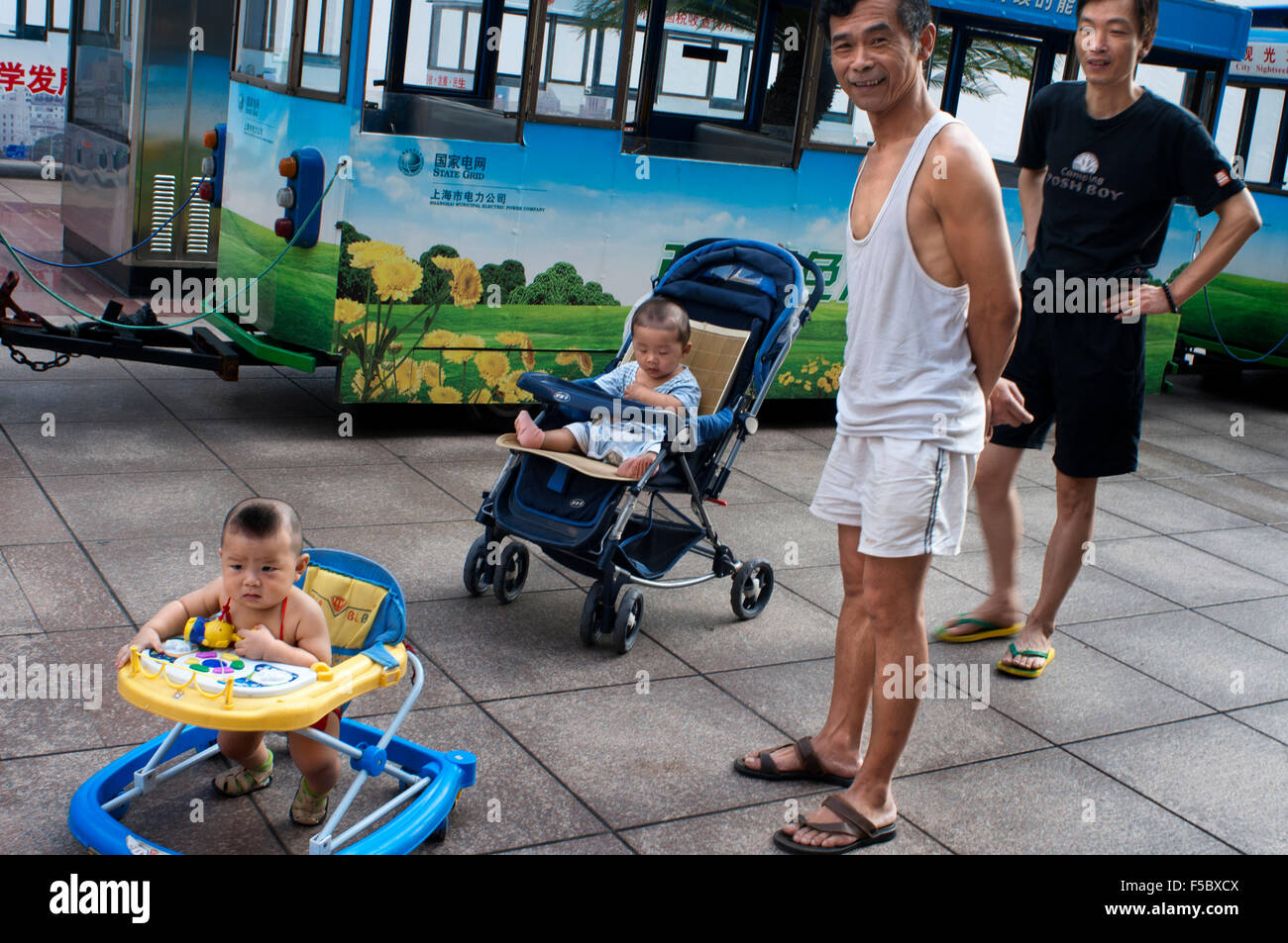 Fathers take car of his children in the streets of Shanghai. Shanghai has a lot to offer your kids when they get tired of being Stock Photo