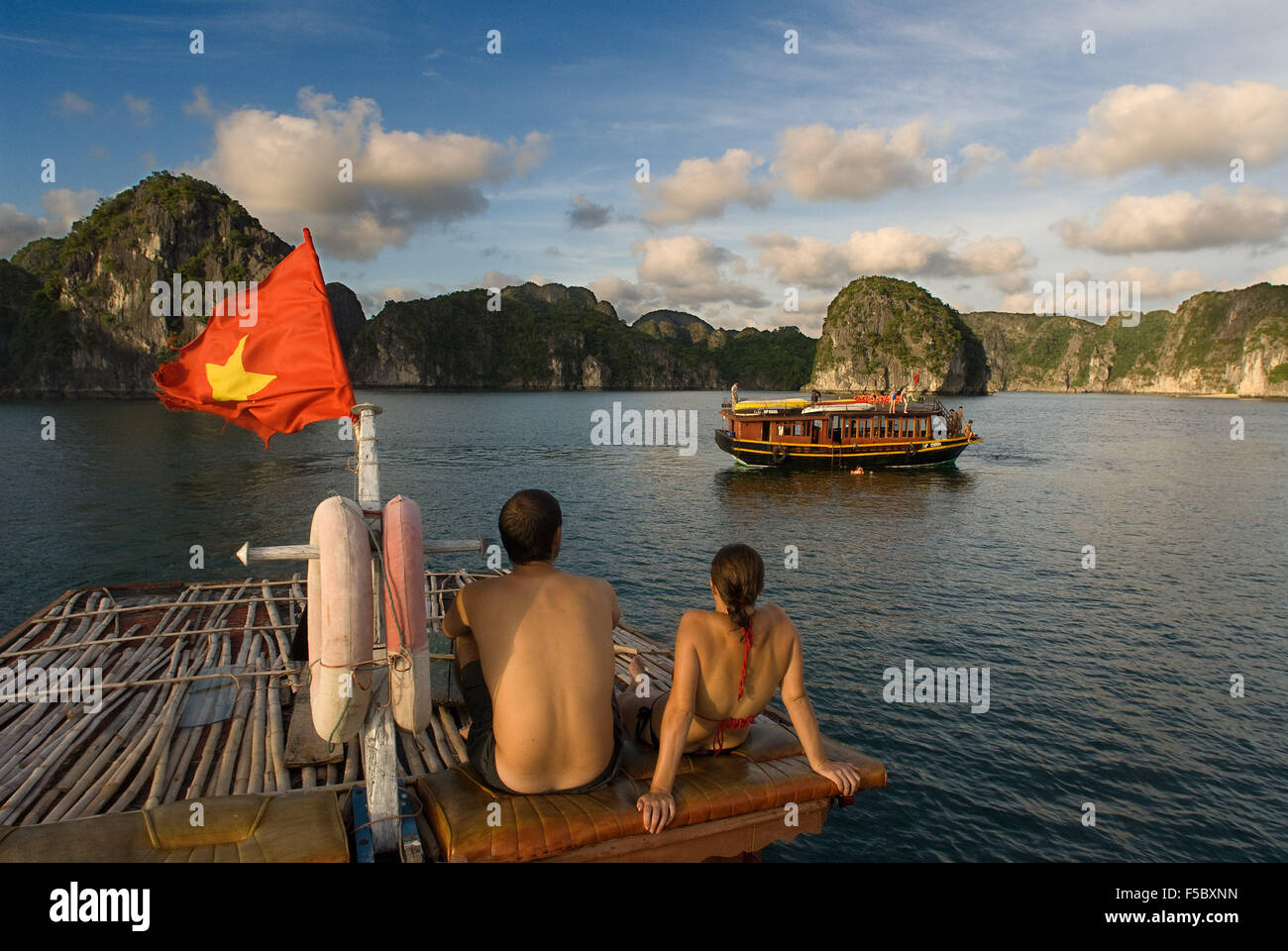 Romatic couple inside a Chinese Junk, Halong Bay Tourist Boat Tour, Vietnam. Junk, boat sailing amongst karst limestone mountain Stock Photo