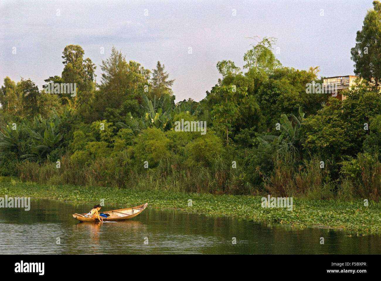 Nice girl clean the clothes inside a wooden sampan makes its way up the brown waters of the Perfume River in Hue, Vietnam. Stock Photo