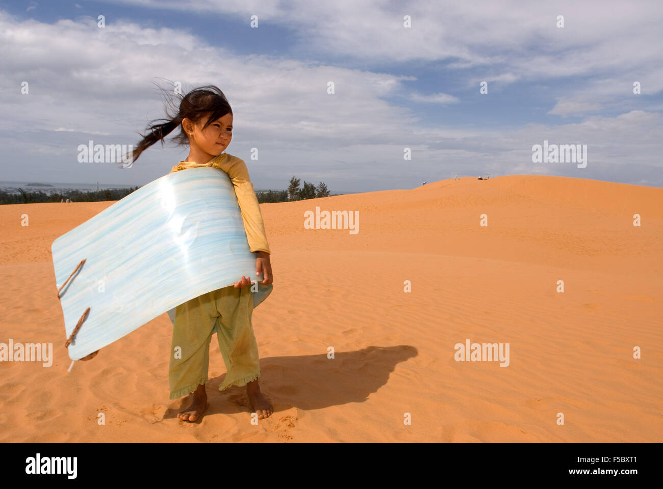 Mui Ne, Vietnam. Young girl with sand sled for hire at the White Sand Dunes. Asia, outside, dunes, scenery, Mui, Mui Ne, nature, Stock Photo