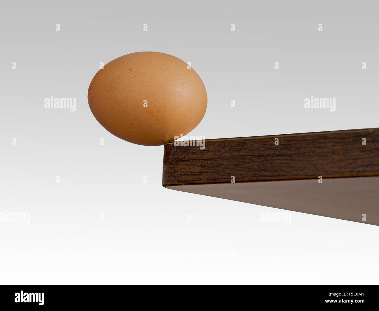 Real egg. Balanced on edge of table. Tipping point. Stock Photo