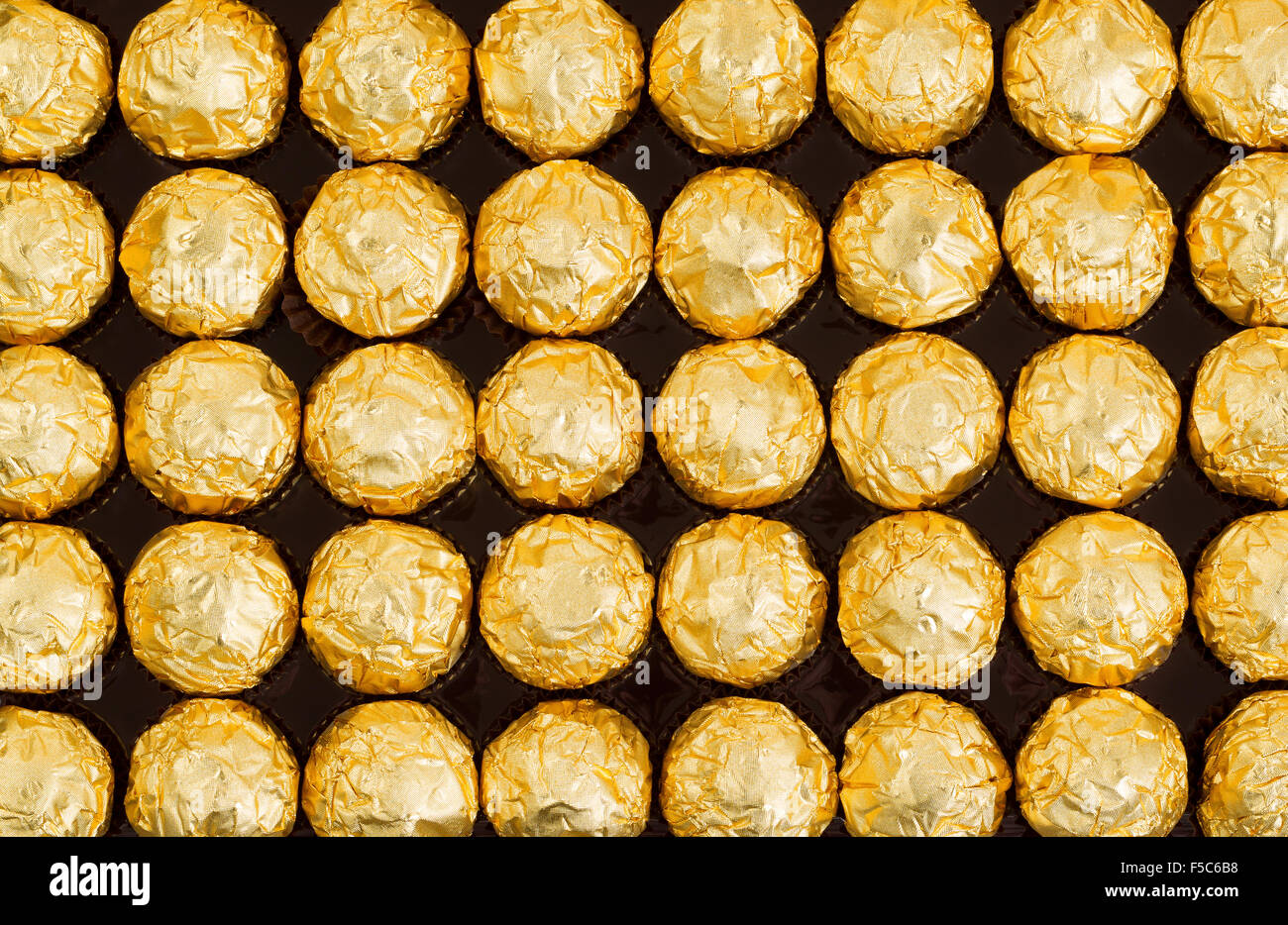 Filled frame of candies wrapped in golden tinfoil. Perfect for the holidays. Stock Photo