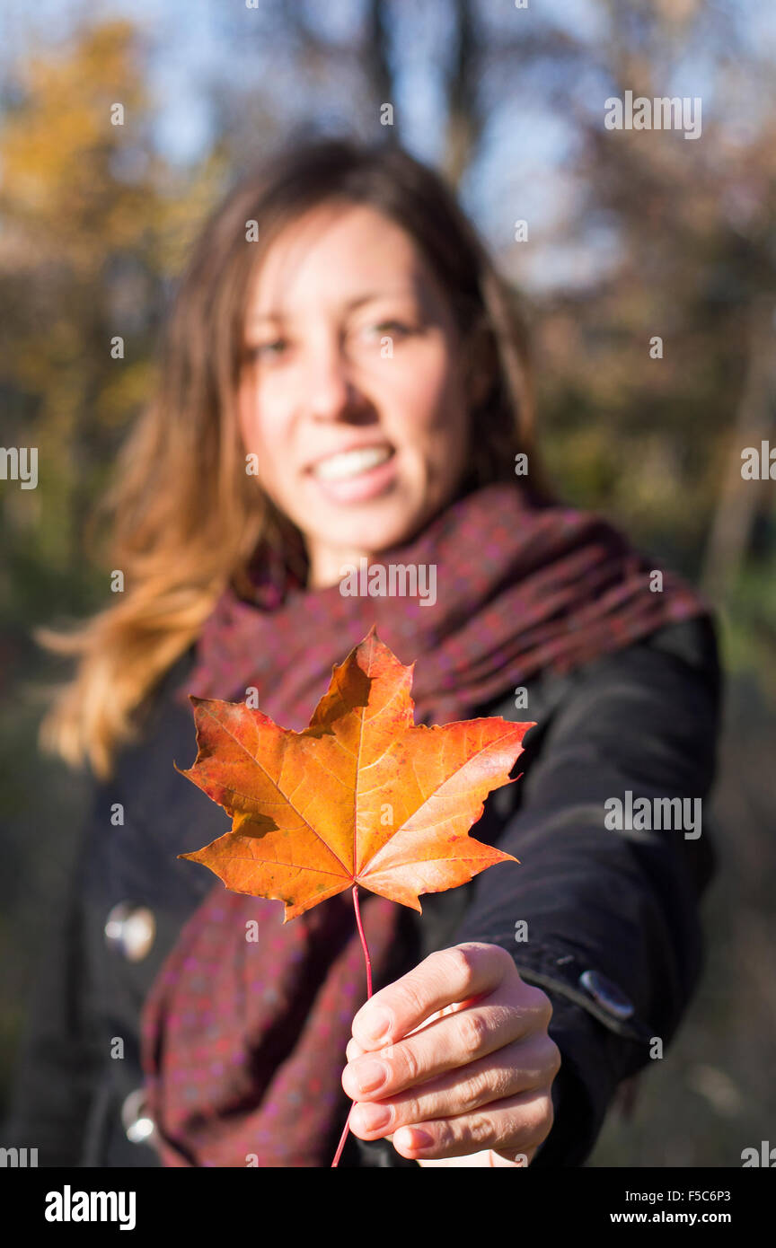Red autumn leaf in girl hands. Girl holding red autumn leaf in the park. Subtle artificial vignette Stock Photo