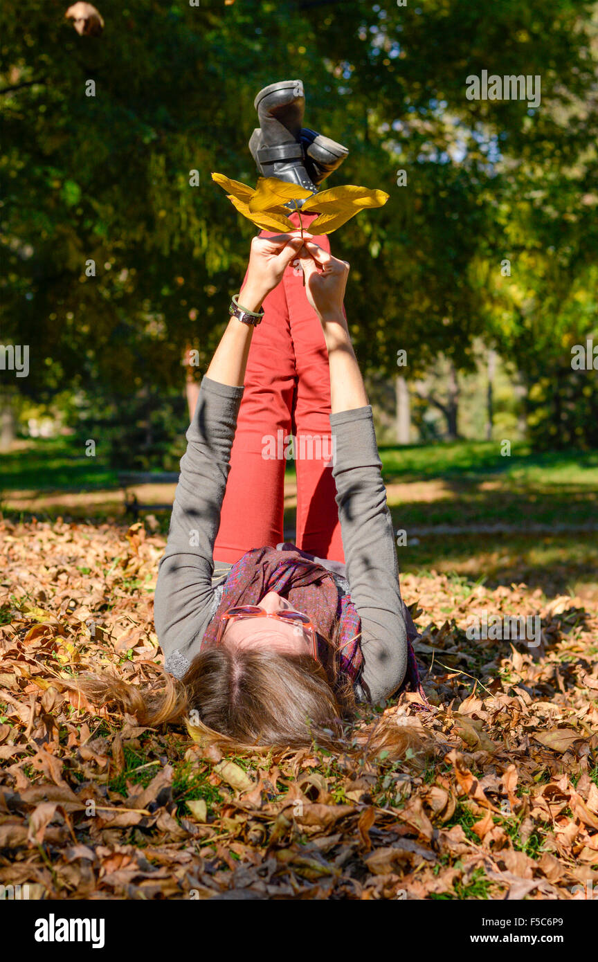 Happy girl lying on yellow autumn leaves in the park Stock Photo - Alamy