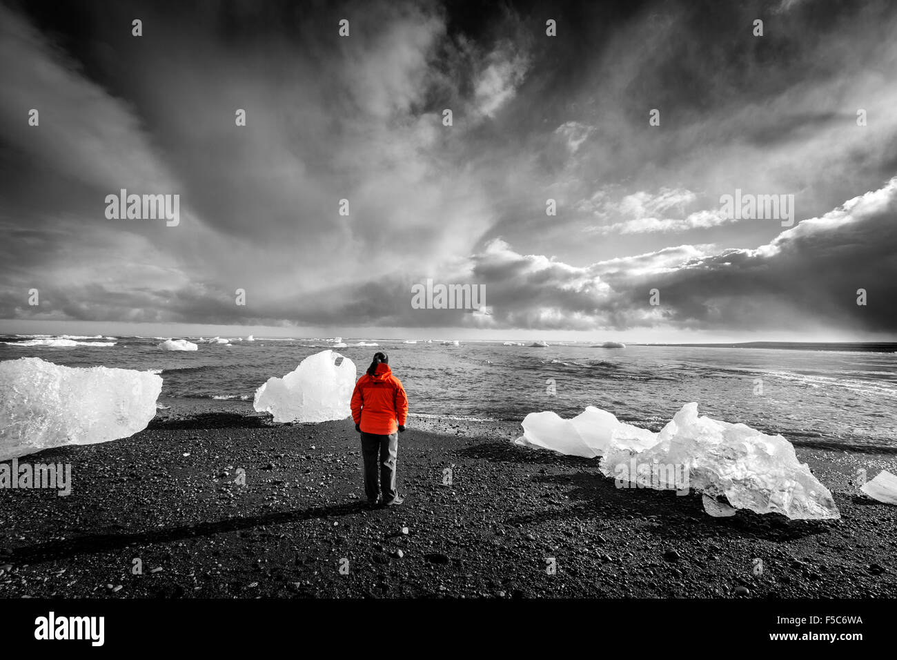 Tourist standing among ice pieces on a beach in southern Iceland. Selective color image Stock Photo