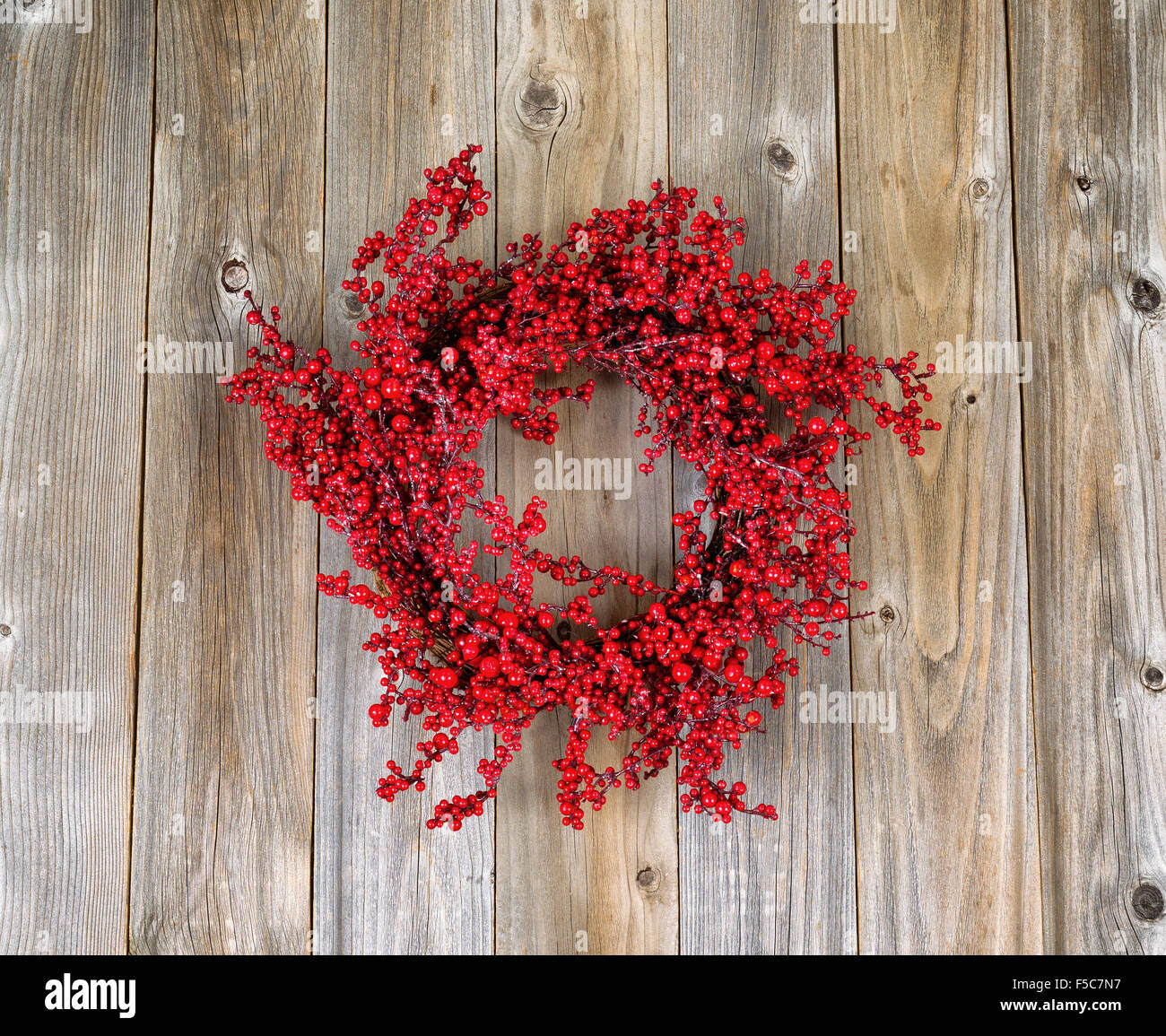 Red holly berry wreath on rustic wood. Boards in vertical layout. Stock Photo