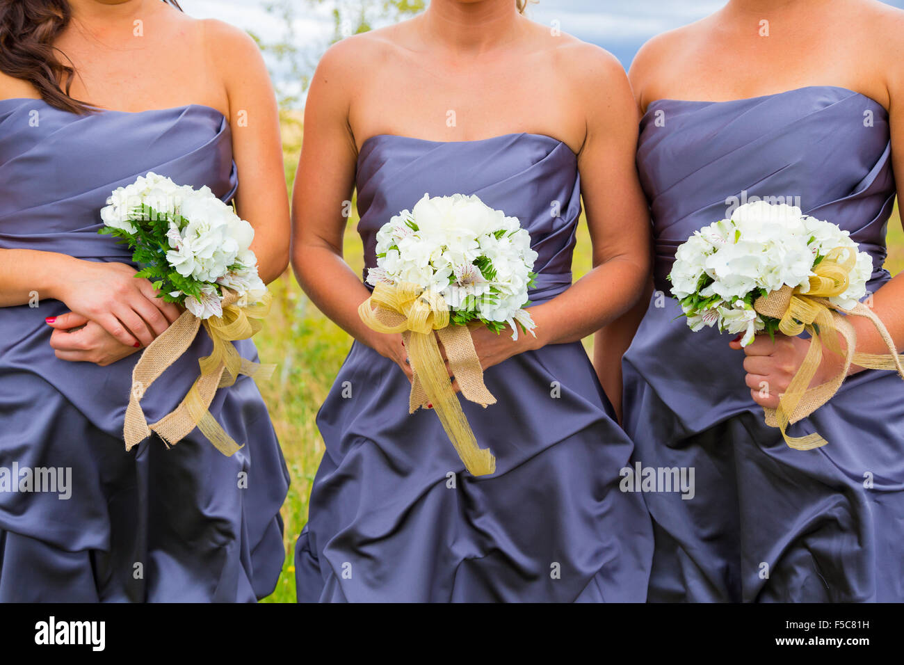 Bridesmaid holding flowers in a white bouquet on a wedding day. Stock Photo