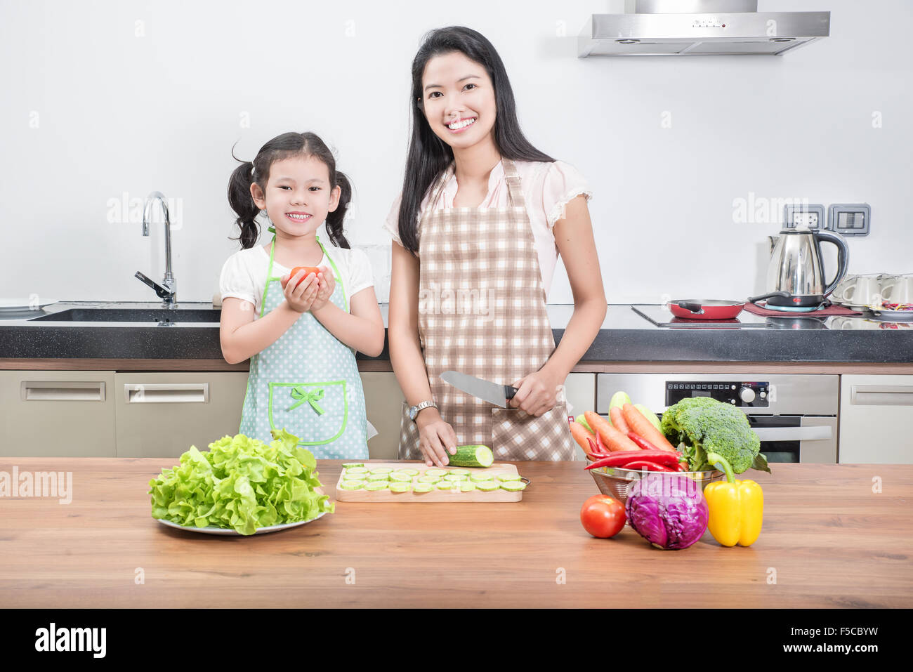 family, children and happy people concept - Asian mother and kid daughter cooking in the kitchen at home Stock Photo